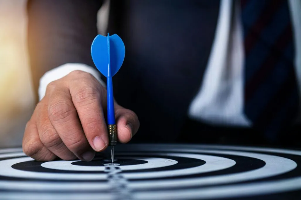A hand holding a dart on a bullseye